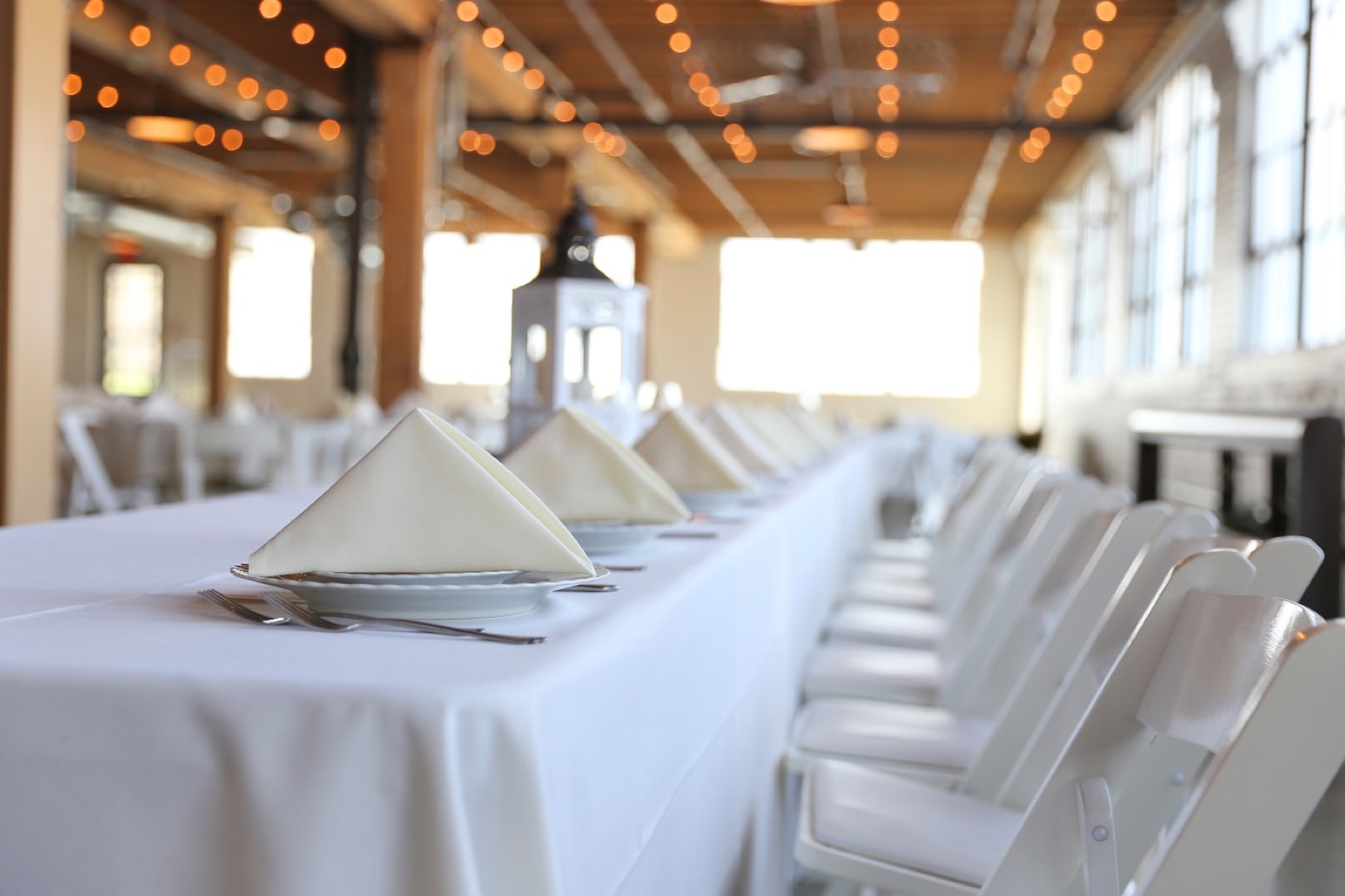 Long dinner table under warm string lights for a milestone celebration